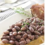 Cooked red beans on crusty bread with herbs, and ham.