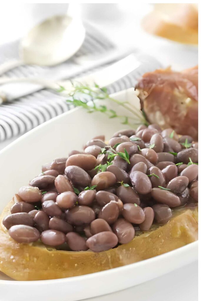Cooked red beans on crusty bread with herbs, and ham.