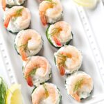 Cucumber rounds with cream cheese spread, shrimp, dill, and lemon wedges.