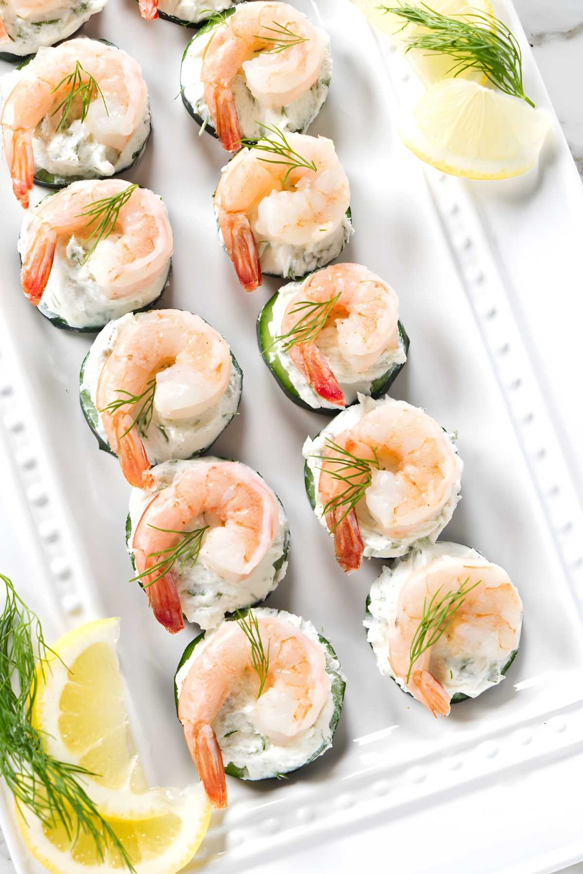 Cucumber rounds with cream cheese spread, shrimp, dill, and lemon wedges.
