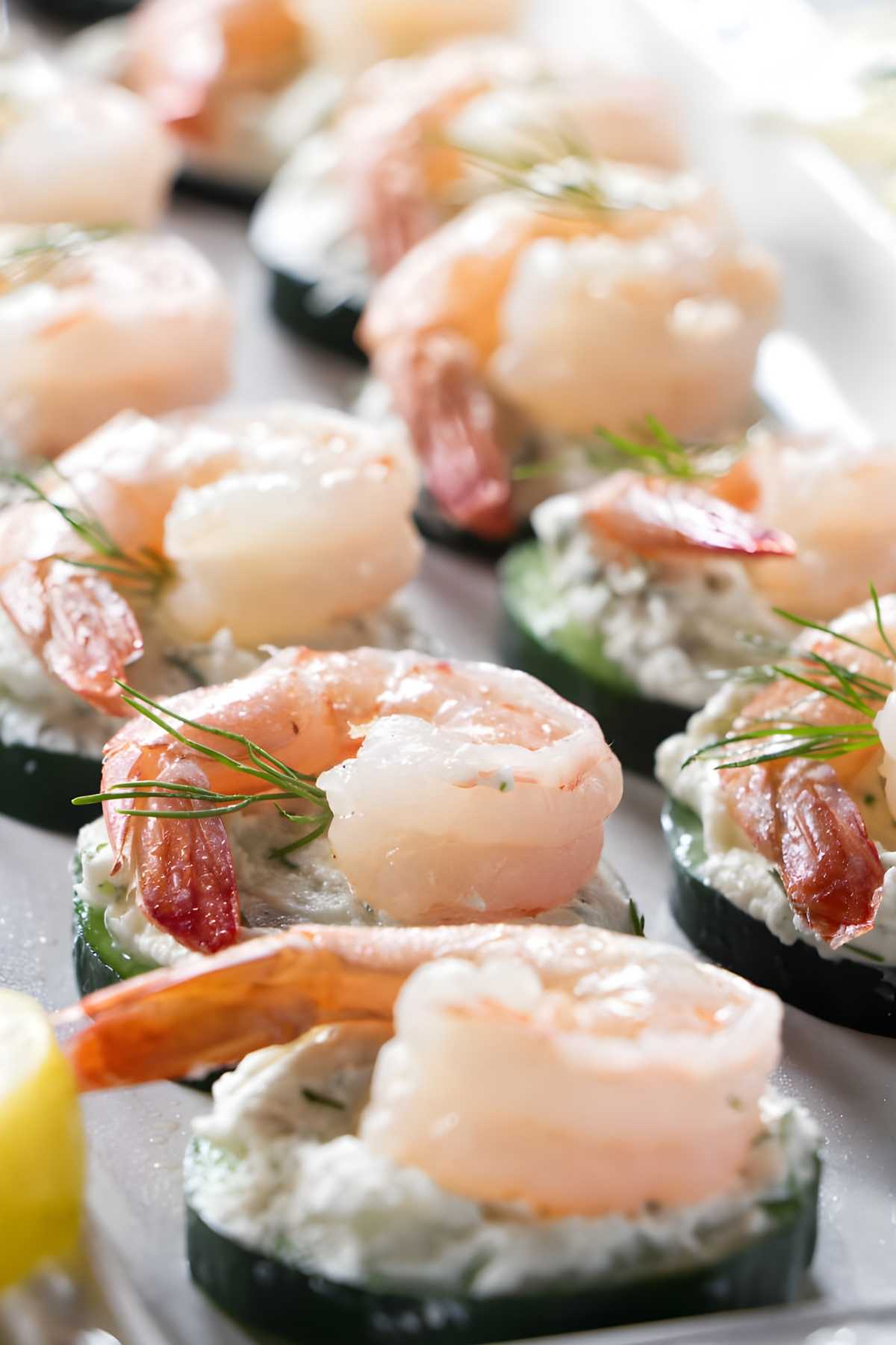 Cucumber slices with creamy spread, shrimp, and dill neatly arranged on platter.
