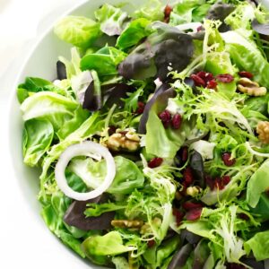 Green salad with leafy greens, red onion, walnuts, and cranberries and gorgonzola.