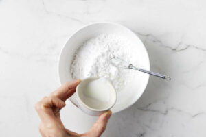 Adding milk to powdered sugar.