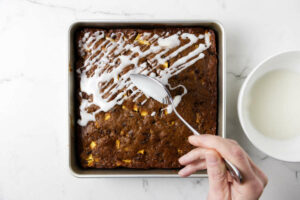 Drizzling icing over a apple date cake.