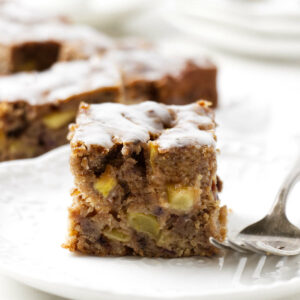 A slice of a date apple cake on a white plate.