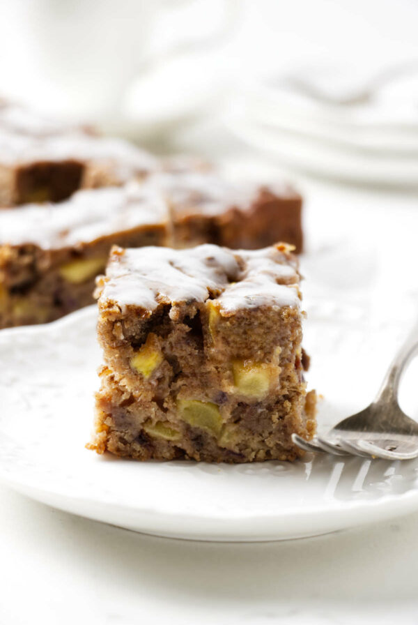 A slice of a date apple cake on a white plate.
