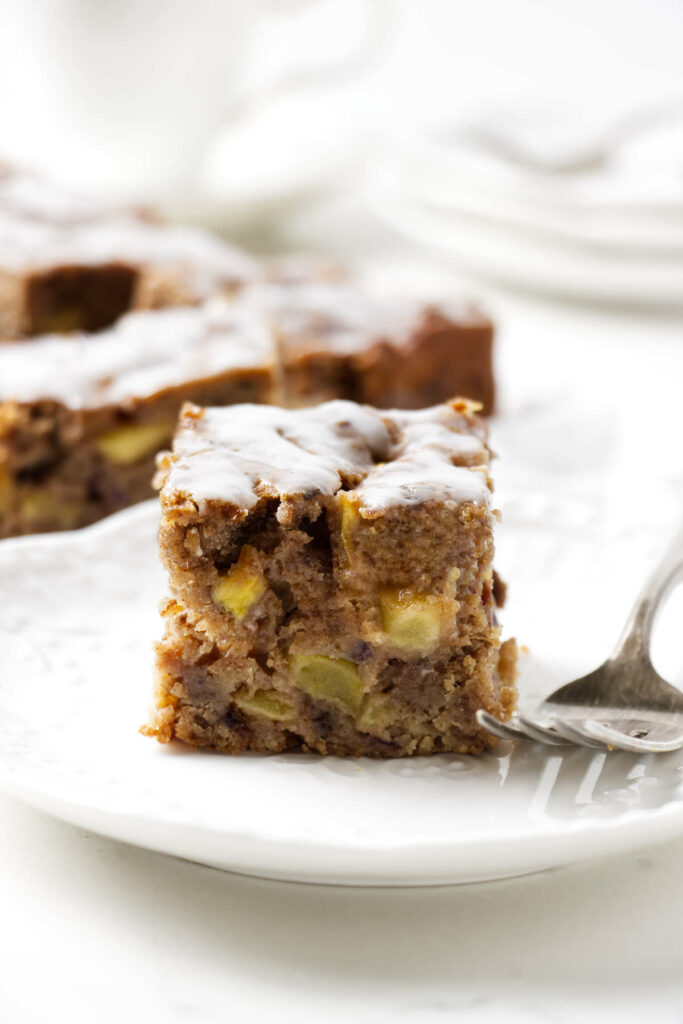 A slice of a date apple cake on a white plate.