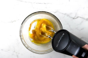 Beating the eggs and sugar in a mixing bowl.