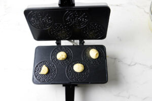 Dropping small amounts of Italian pizzelle batter on a hot pizzelle maker.