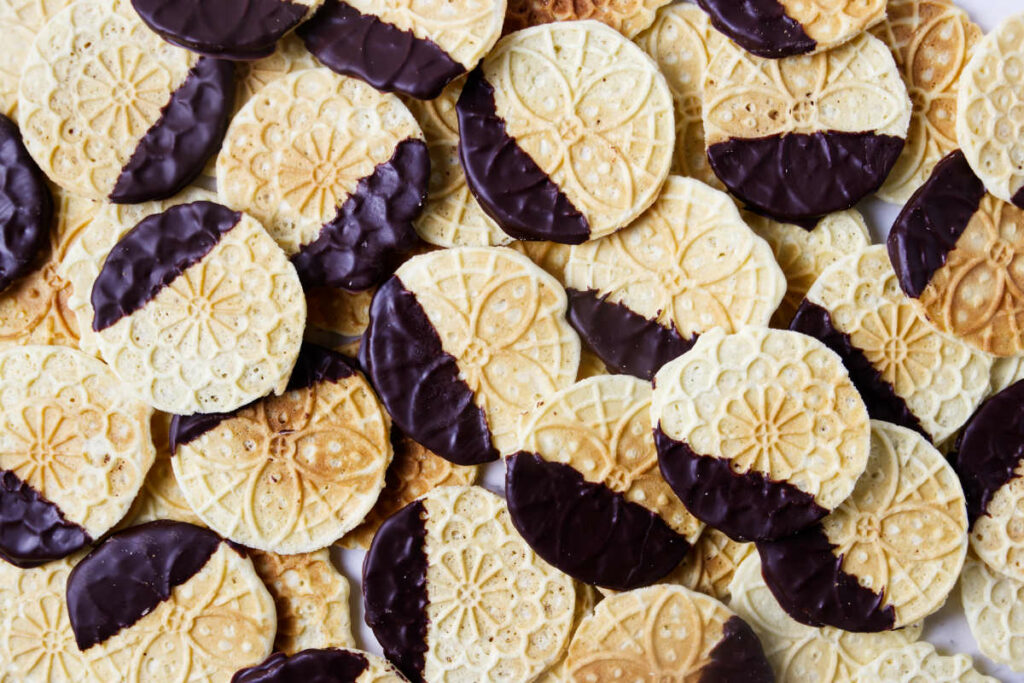 A pile of chocolate dipped pizzelle cookies on the counter.