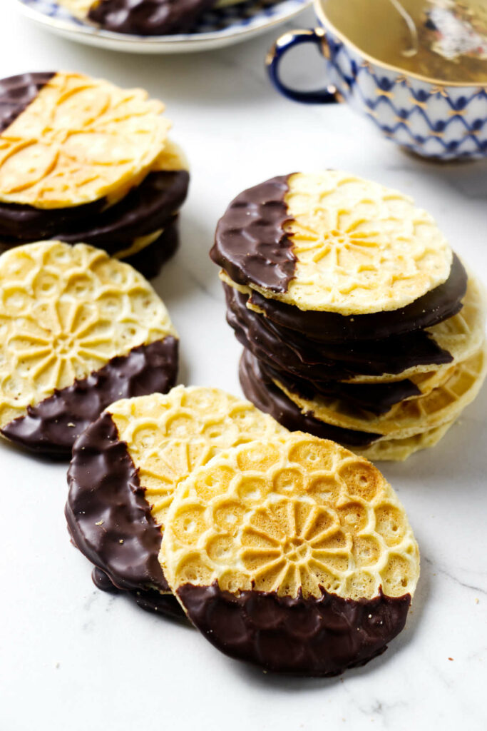 Several mini pizzelles on a white counter next to a cup of tea.