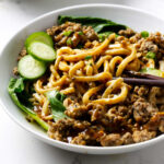 Dan dan noodles in a white bowl with chop sticks.