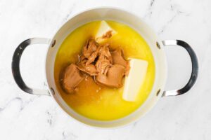 Melting butter and peanut butter on the stovetop.