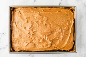 Spreading icing over a peanut butter sheet cake.
