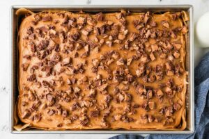 A peanut butter sheet cake topped with chopped peanut butter cups.