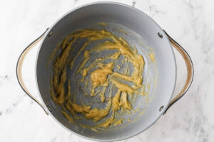 Stirring flour into the butter to make a roux.