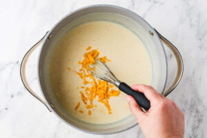 Adding cheese to the sauce.