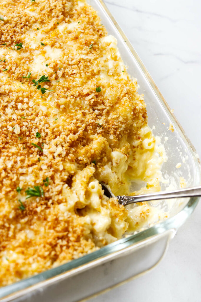 A spoon in a 13 x 9 inch casserole dish of mac and cheese.
