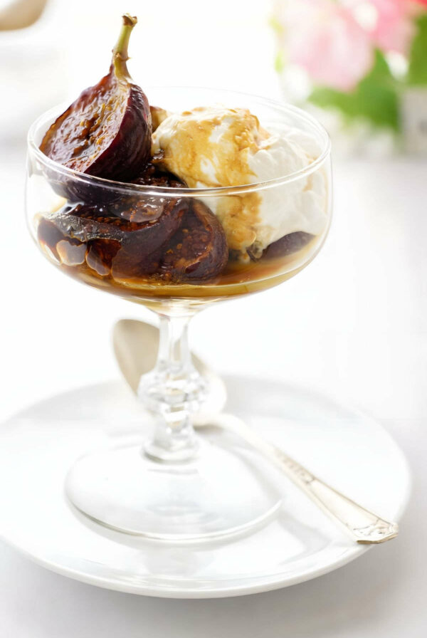 A dish filled with honey caramelized figs and a scoop of creme fraiche.