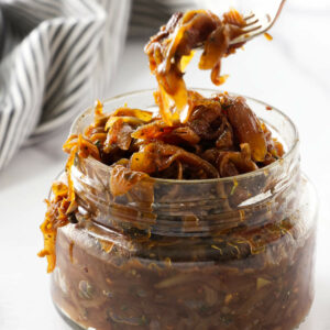 Scooping sweet onion marmalade out of a jar.