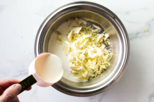 Melting white chocolate with cream in a saucepan.
