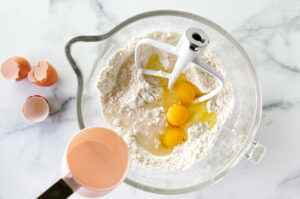Adding the eggs to the dough.