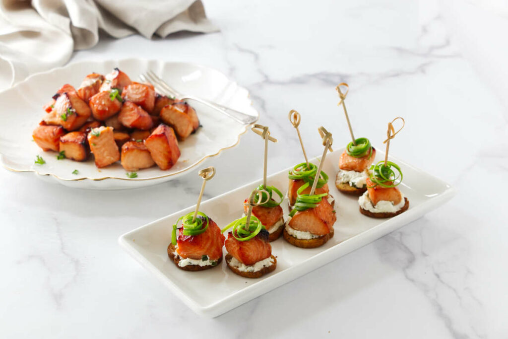 Placing salmon bites on small rounds of toast for an appetizer.