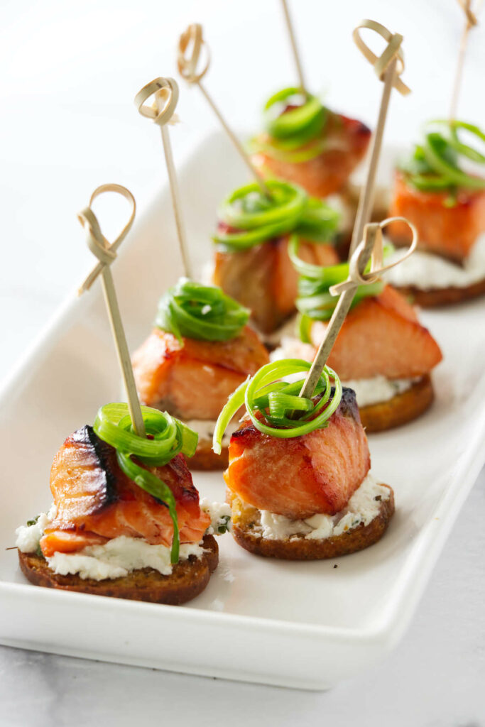 Salmon bite appetizers on rounds of toast and creamy cheese.