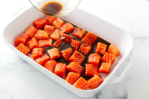Adding marinade to chunks of salmon.