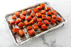 Placing chunks of salmon on a baking sheet.