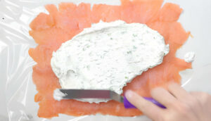 Spreading cream cheese on top of the salmon.