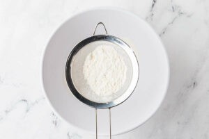 Sifting the dry ingredients into the mixing bowl.