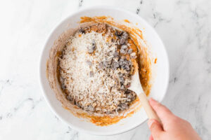 Stirring the raisins and coconut into the muffin batter.