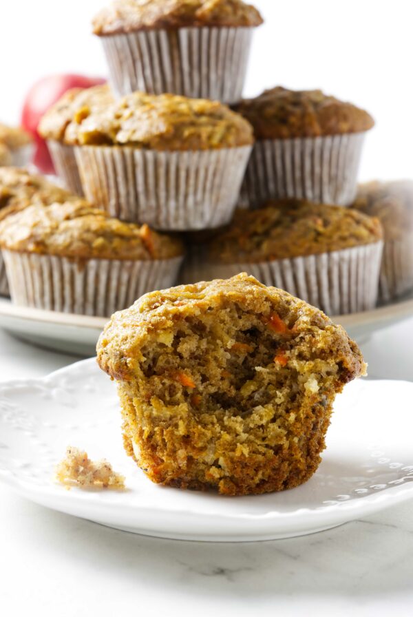 A partially eaten sourdough carrot and apple muffin with more muffins in the back.