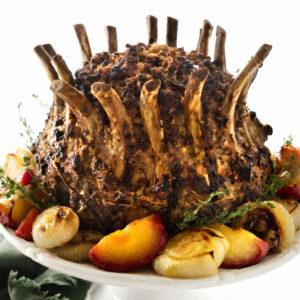 A crown pork roast on a platter with stuffing in the center and veggies on the outside.