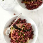 Two bowls of red beans and herbs on toast, with water and rosemary.