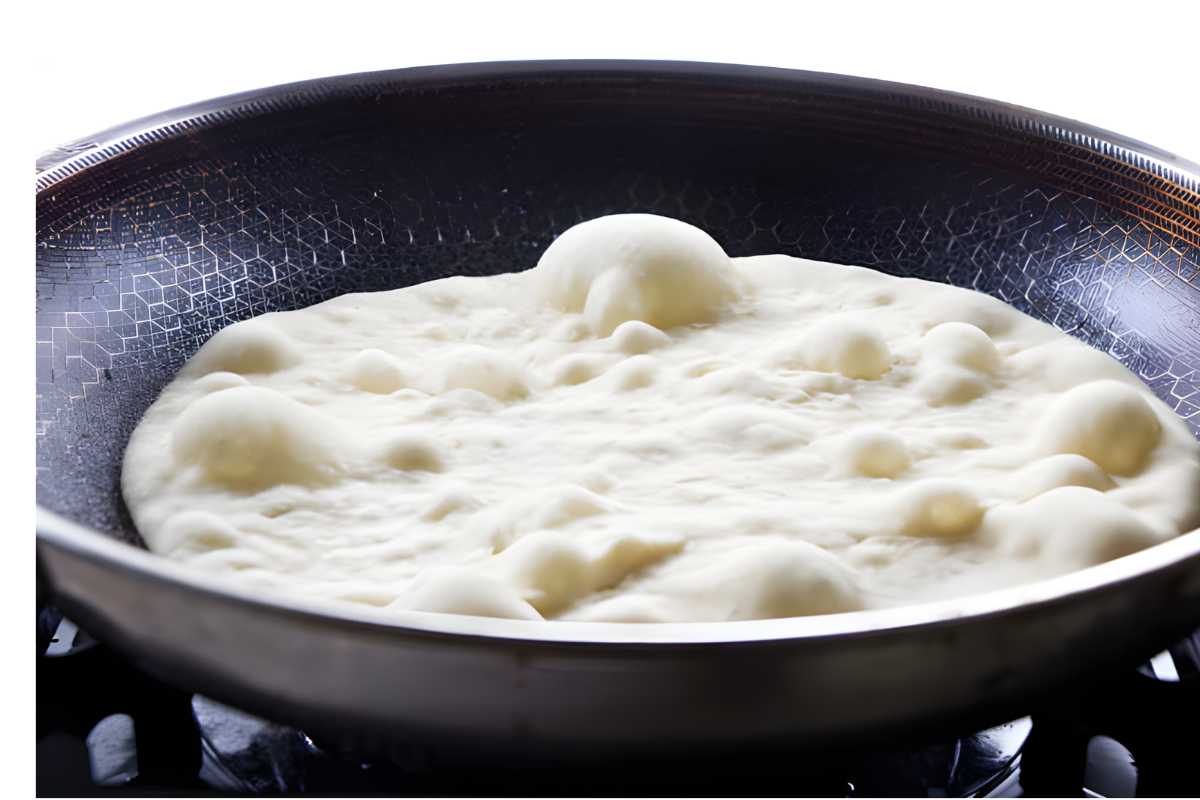 Close-up of dough bubbling in a frying pan on the stove.