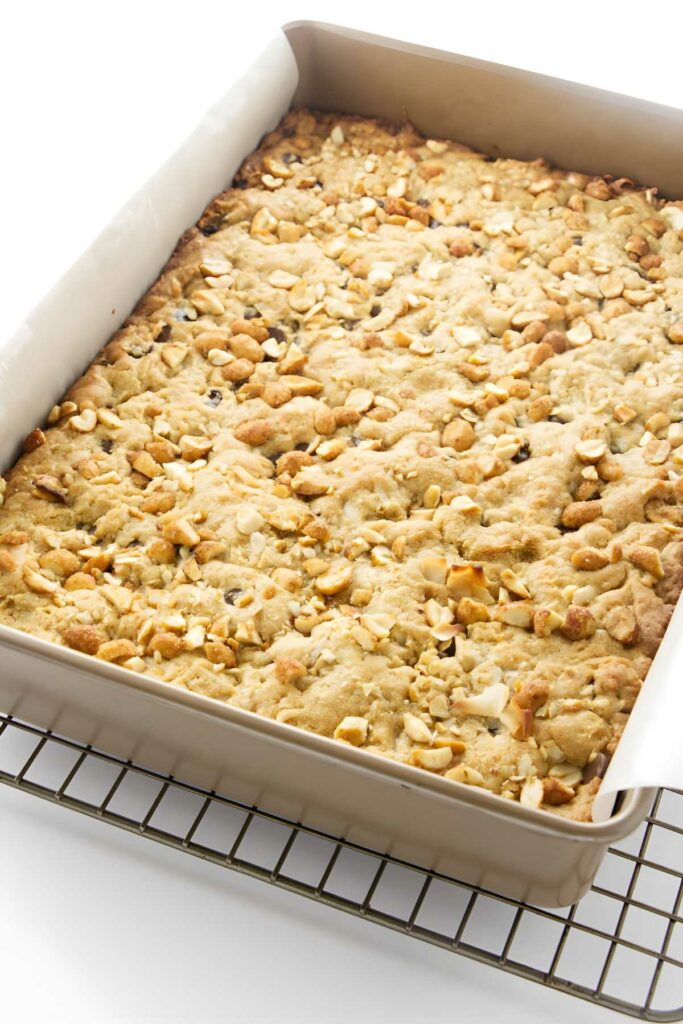 Square pan of peanut butter coconut bars cooling on wire rack, white background.