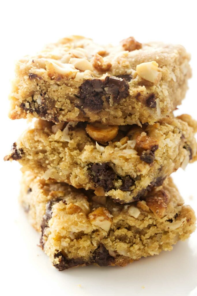 Three chewy peanut butter and coconut bars stacked on each other.