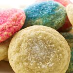 Sugar cookies on a plate, some with pink and blue sprinkles, others lightly sugared.