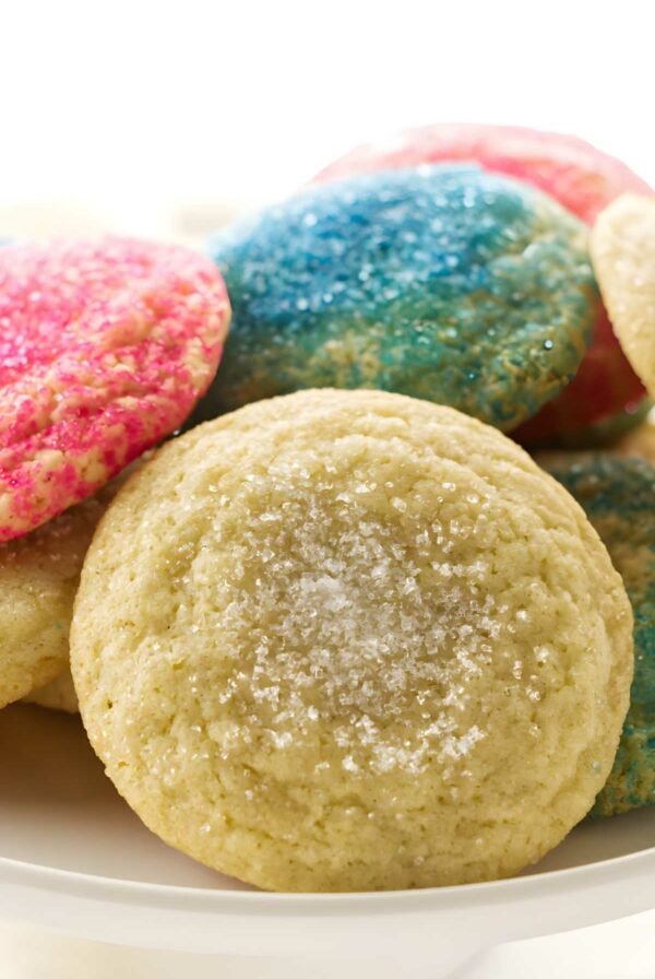 Sugar cookies on a plate, some with pink and blue sprinkles, others lightly sugared.