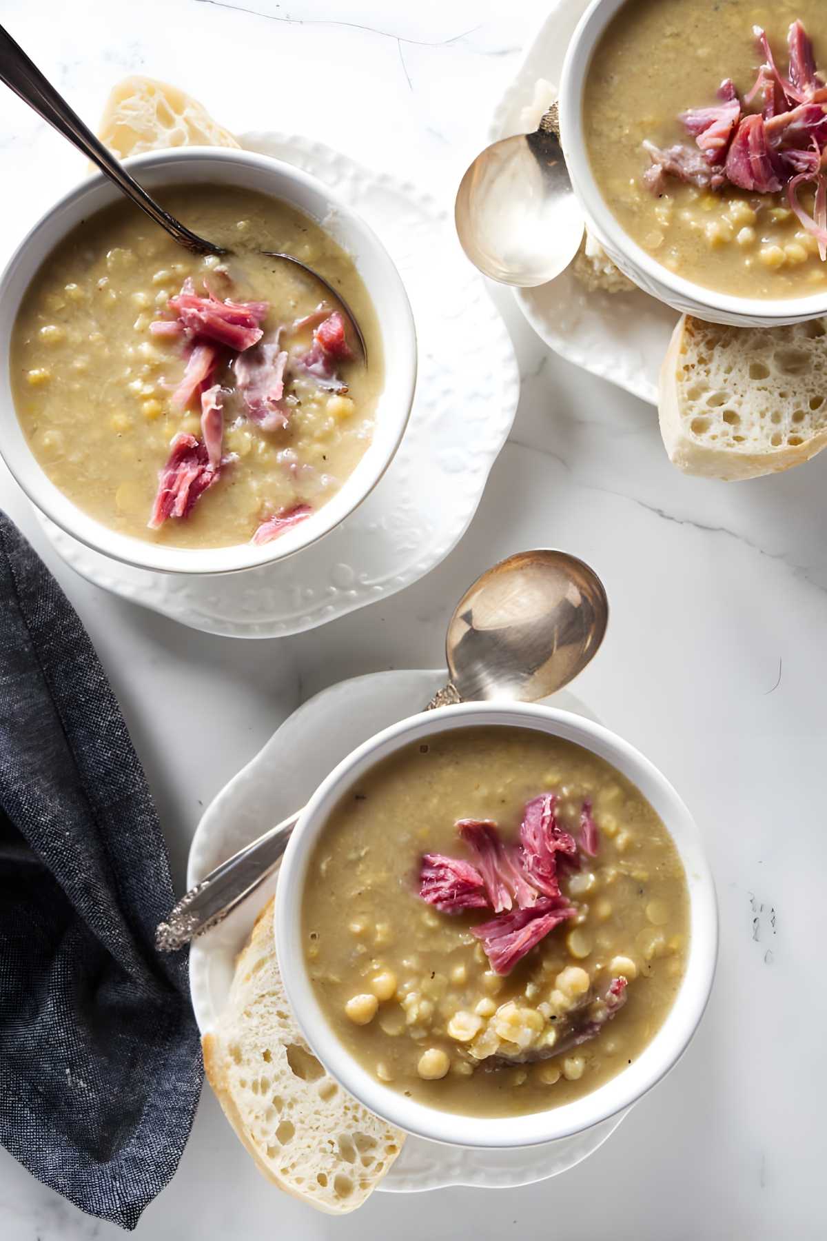 Three bowls of yellow pea soup with shredded ham.