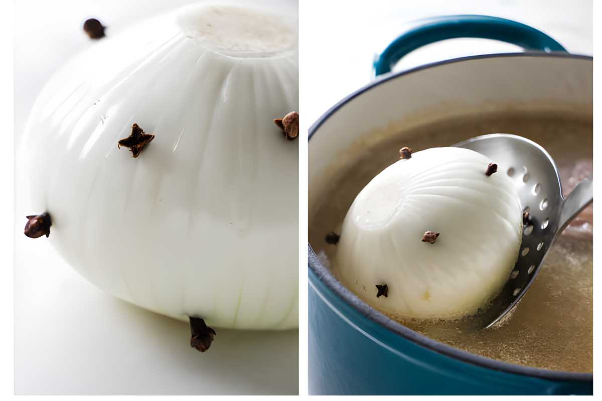 Peeled white onion with cloves, on surface and in slotted spoon over broth.