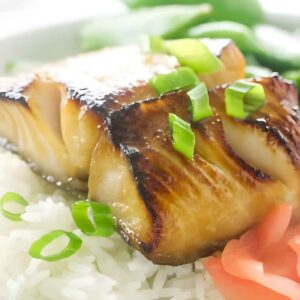A serving of teriyaki black cod on a bed of white rice.