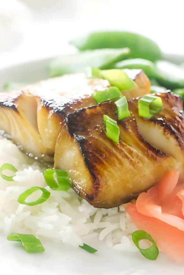 A serving of teriyaki black cod on a bed of white rice.