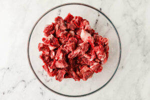 Slices of beef getting seasoned in a bowl.