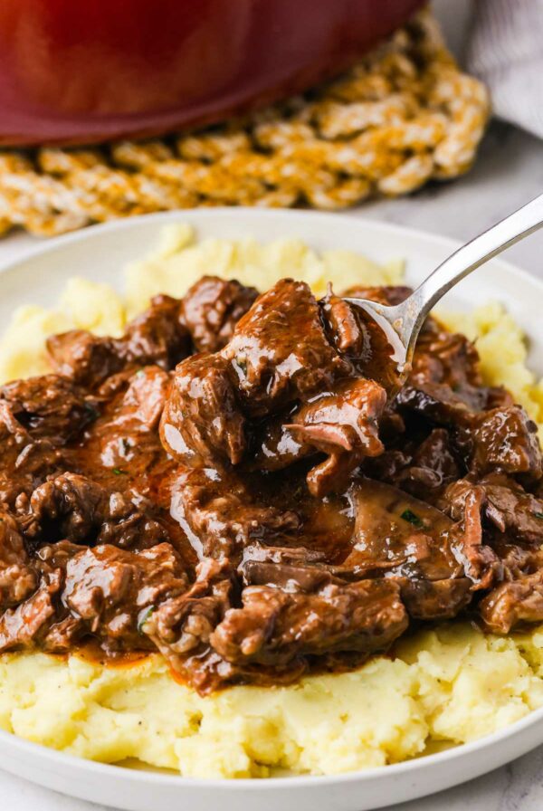 A serving of beef and gravy over mashed potatoes.