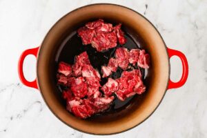 Searing chunks of beef in a hot pot.