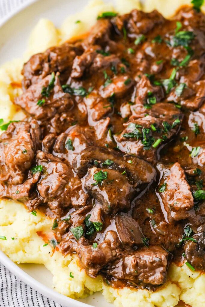 A plate of beef and gravy over mashed potatoes.