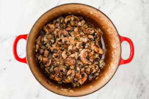 Saut&eacute;ing onions and mushrooms in a pot.